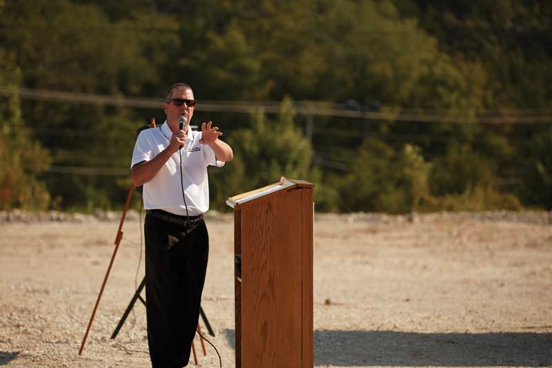Mark Luebbert standing behind a podium at the groundbreaking of Mid America Bank's future location.