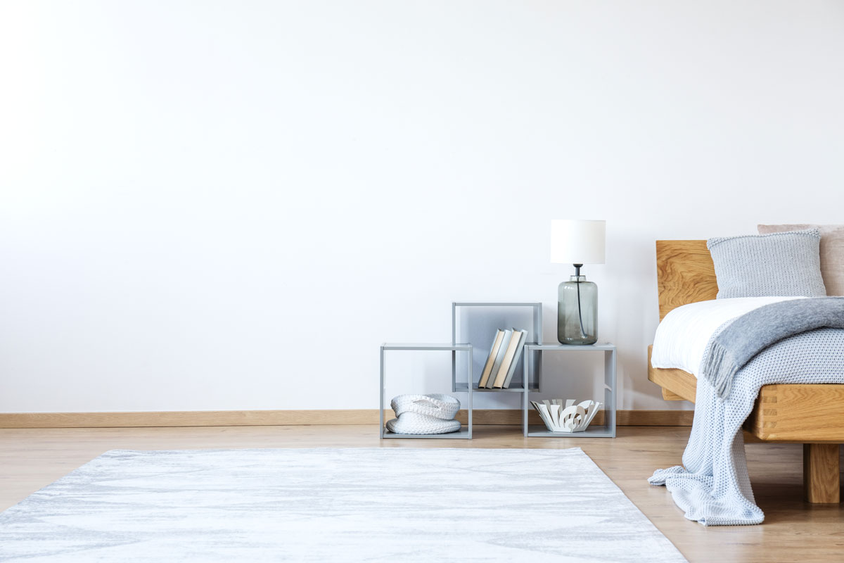 A staged bedroom with cube shelves. A coastal jar lamp sets near the platform bed. A cozy throw lays on the foot of the bed.