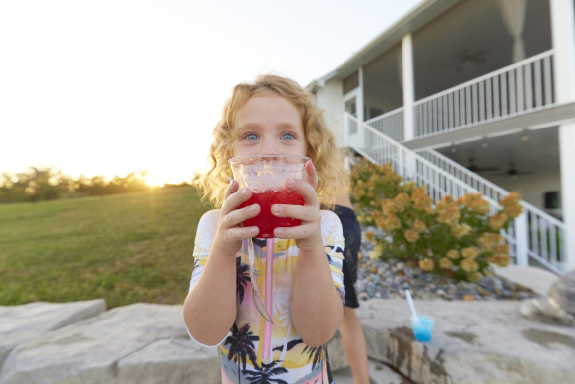 Kid taking sip of juice at a pool party.